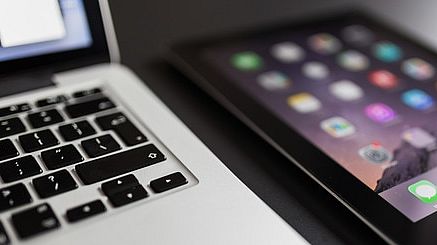 Laptop liegt neben iPad auf einem Tisch.